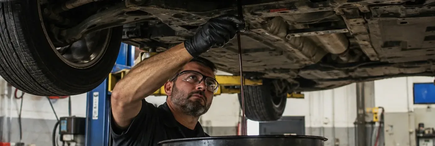 Technician draining engine oil during an oil change